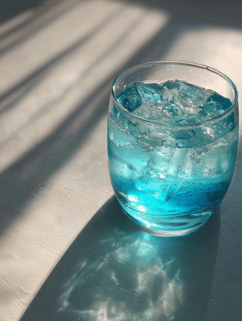 Blue Salt Trick: The Viral Wellness Hack Close-up of blue salt trick drink with icy texture and sunlight reflections.