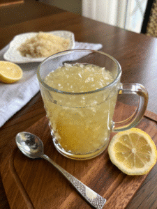 Dr Mark Hyman gelatin recipe in clear glass mug on wood table with lemon and spoon